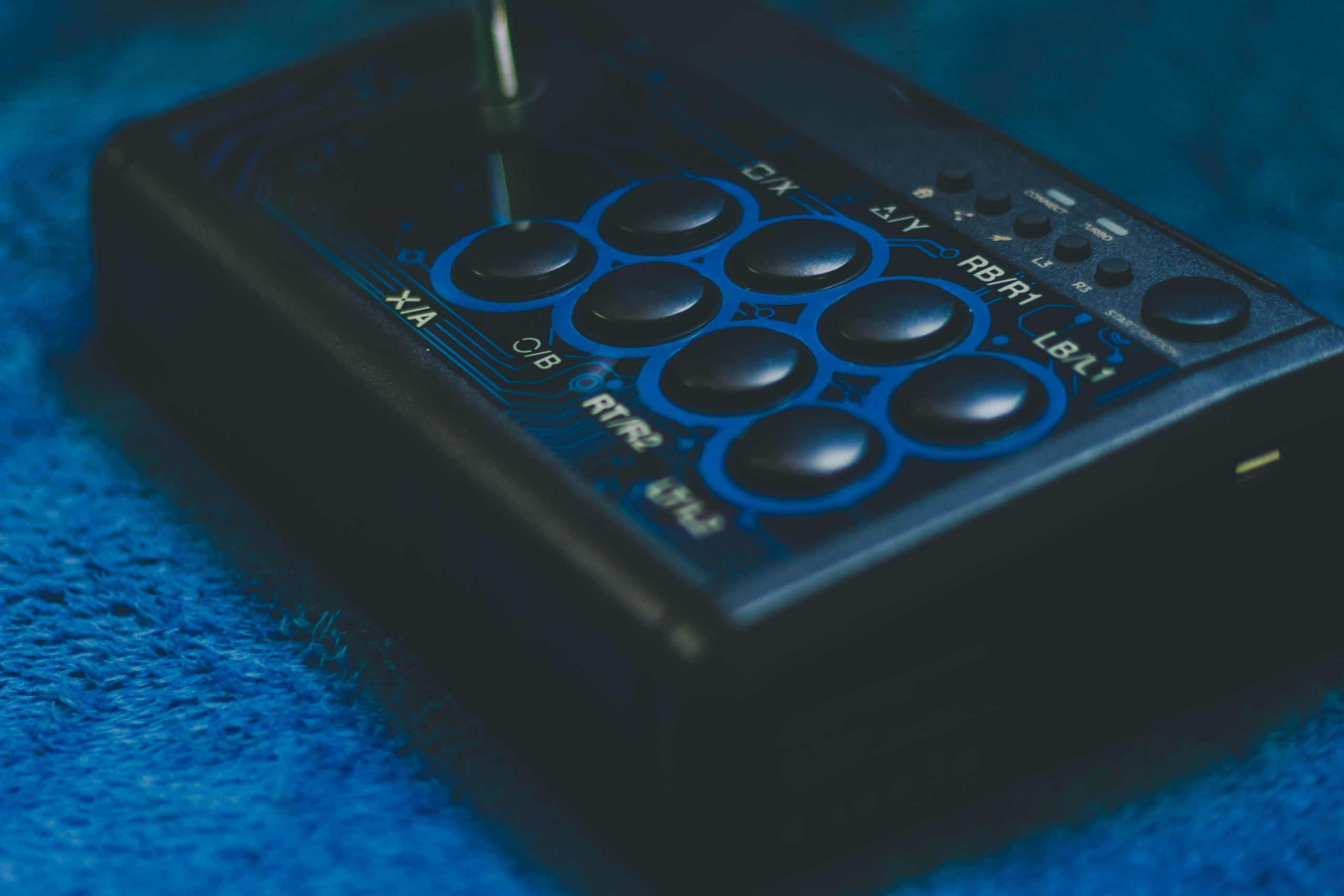 Detailed view of a game controller on a blue surface, highlighting buttons and joystick.