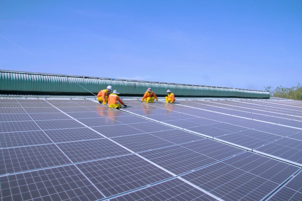 Workers installing solar panels on a sunny rooftop, emphasizing renewable energy and sustainability.